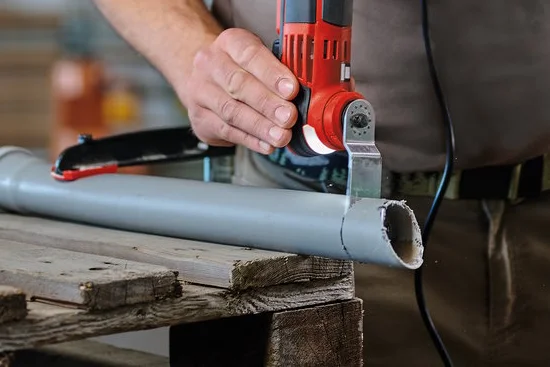 Person schneidet Rohr mit oszillierendem Werkzeug